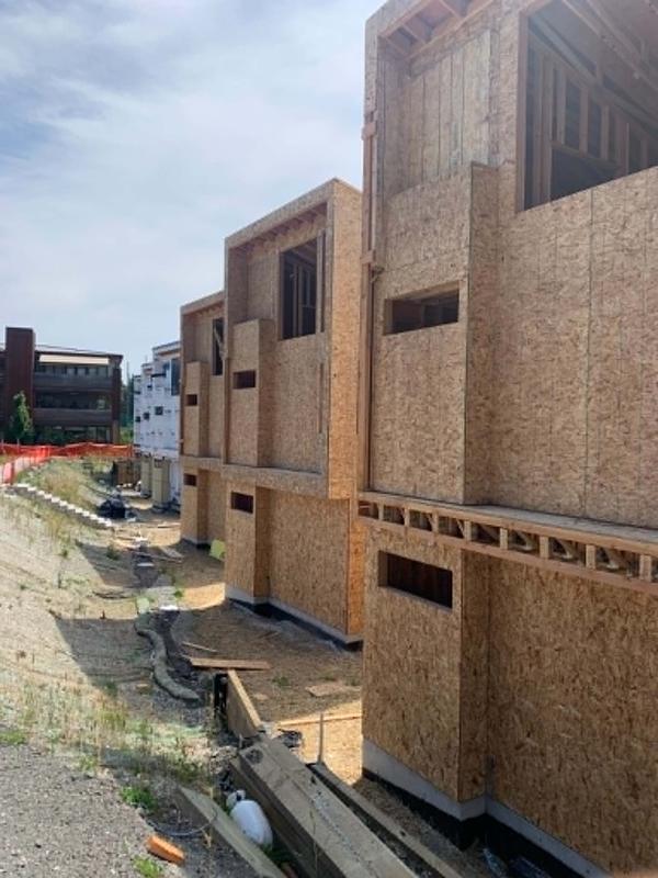 Row of modern townhomes framed with OSB sheathing in an urban setting