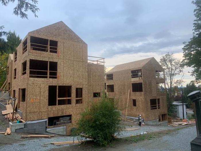 Multi-family townhome buildings under construction with gabled roofs