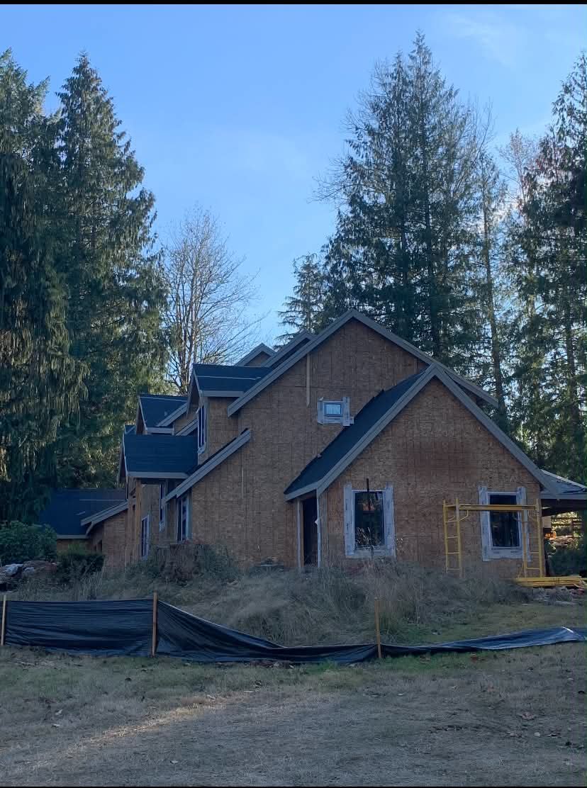 New custom home under construction surrounded by evergreen trees